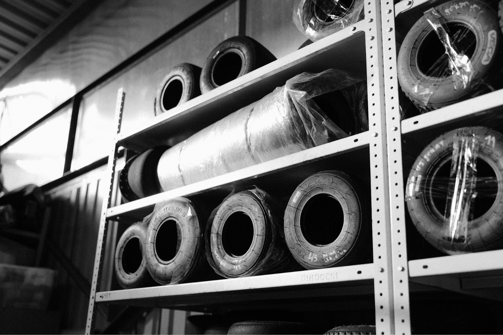 Black-and-white image of tires stored on industrial shelving, representing operational workflow improvements.